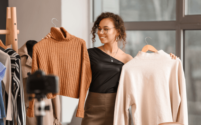 Flat lay of timeless wardrobe staples including a blazer, jeans, loafers, and gold accessories.
